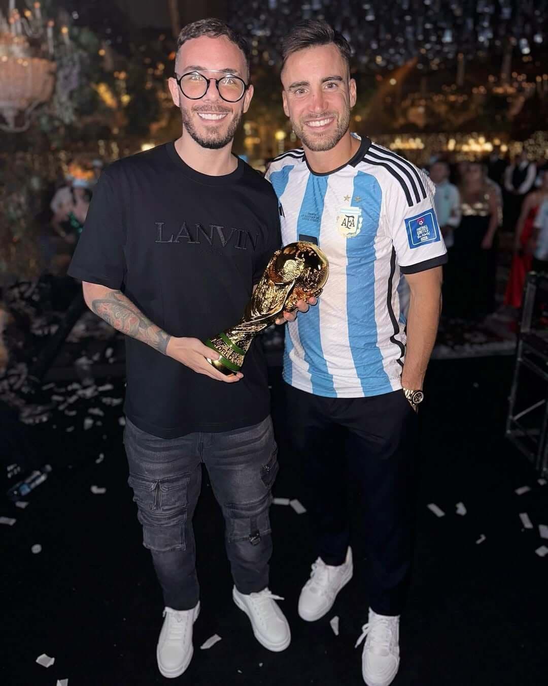 Fer Palacio junto a un invitado que sostiene la Copa del Mundo, entre papelitos
