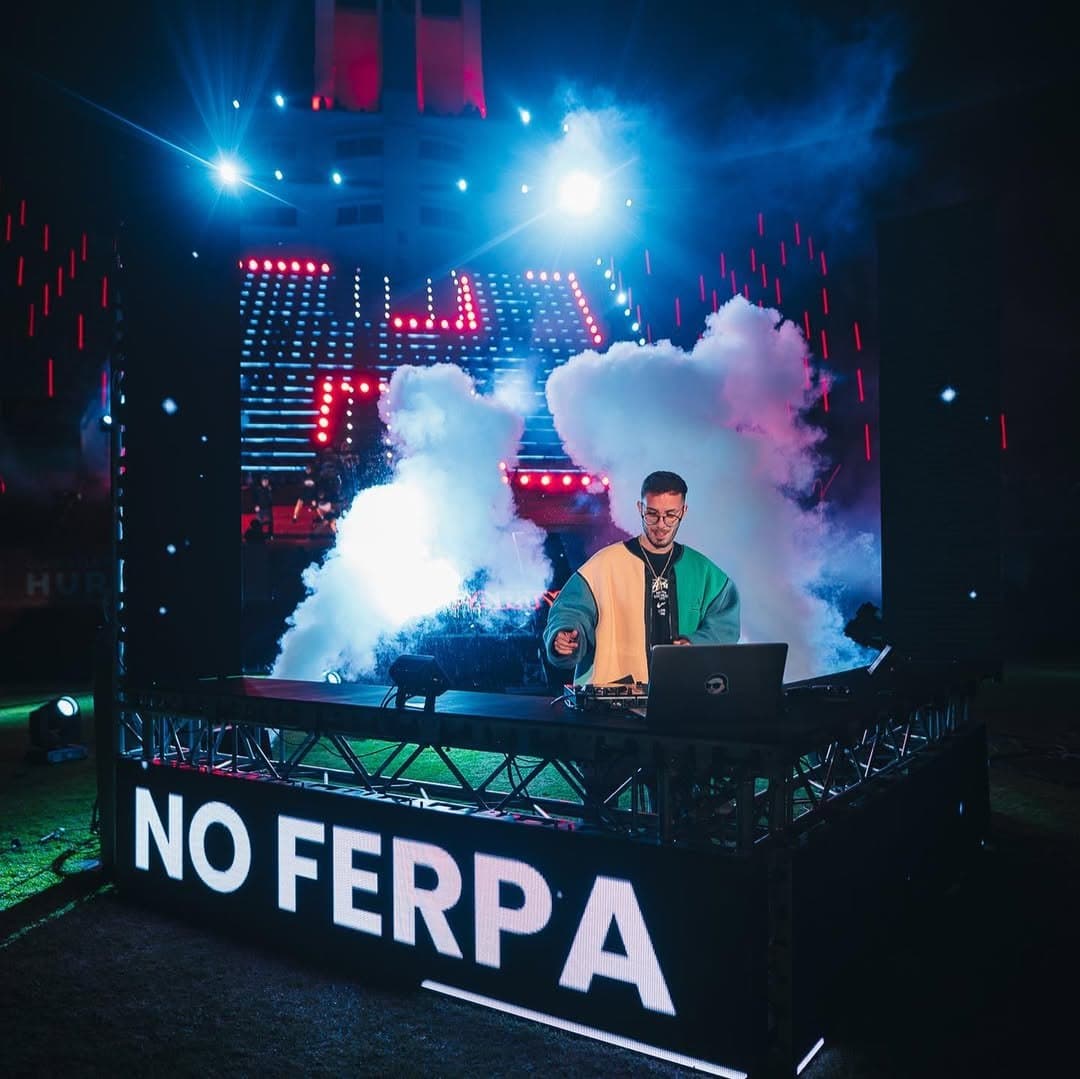 Cabina de DJ con un cartel LED que dice NO FERPA, entre humo y luces